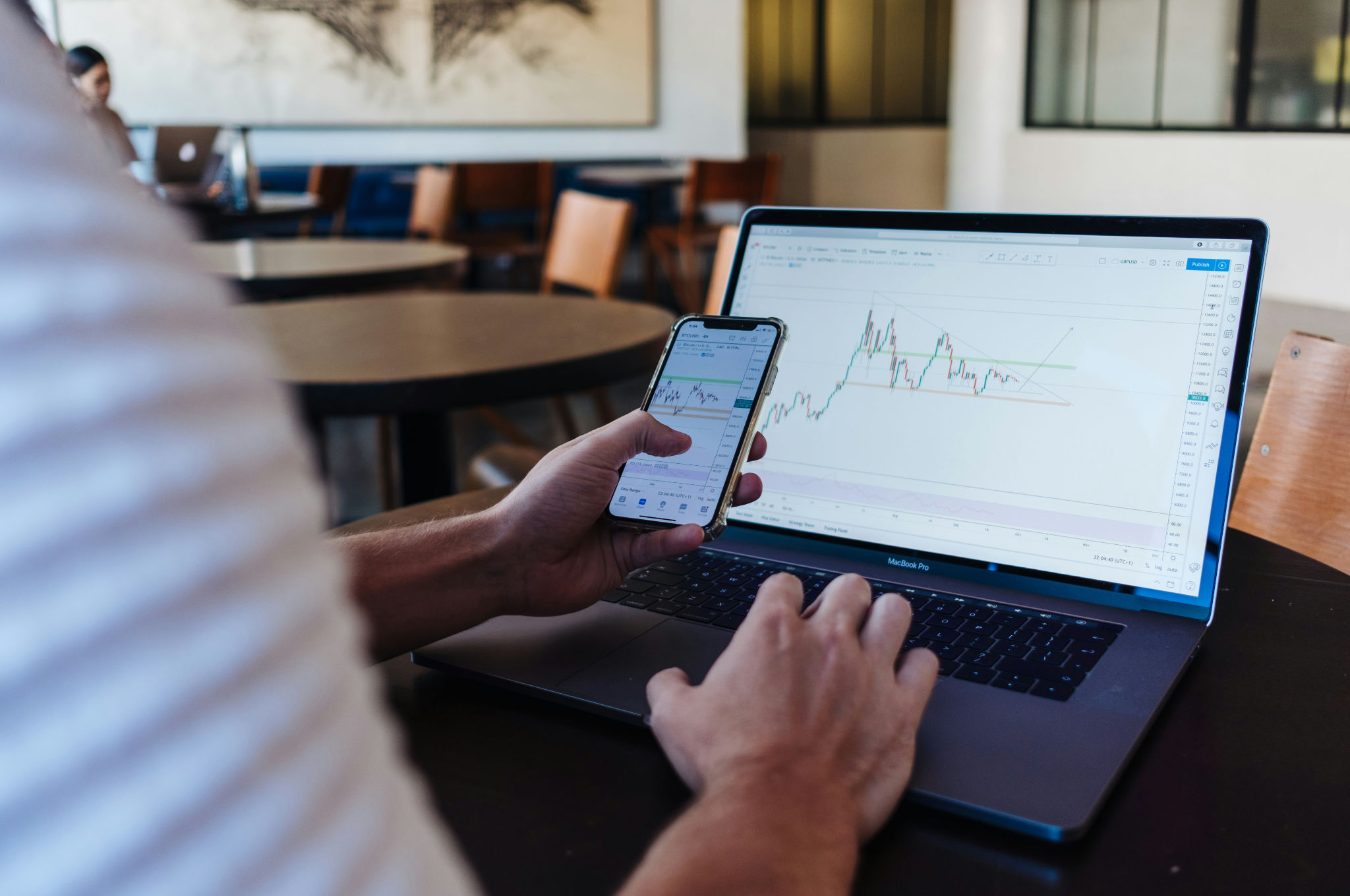 Person using laptop and smartphone with pricing charts